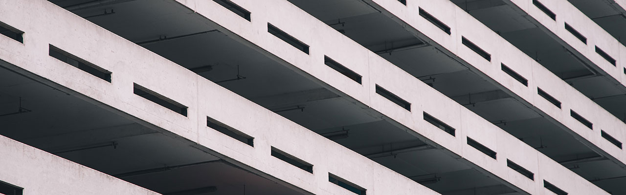 A grey image of the outside of a multi-story car park showing five levels of the car park - car park management services