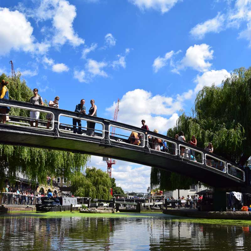 Camden lock bridge in the summer with people looking over the water