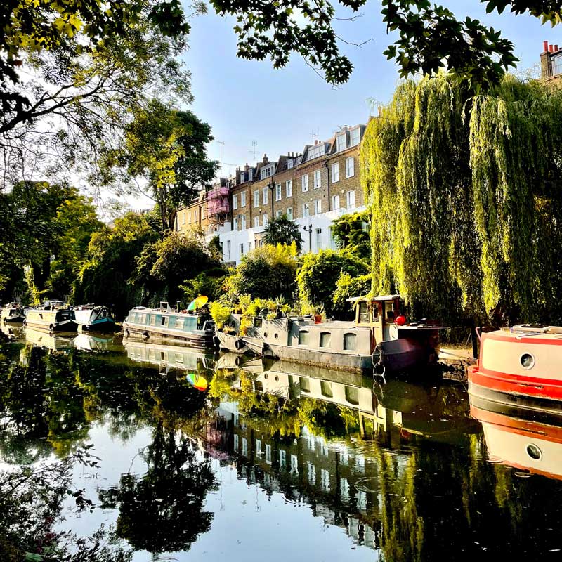 Islington canal boats in the sun - buildings and boats reflected in the calm water